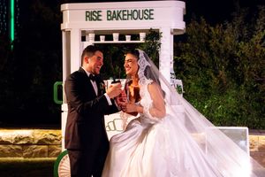 Bride and groom toasting champagne outside Rise Bakehouse at night, celebrating their wedding day.