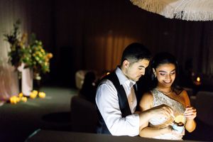 Couple sharing an intimate moment together at a dimly lit wedding reception, illuminated by warm candlelight.