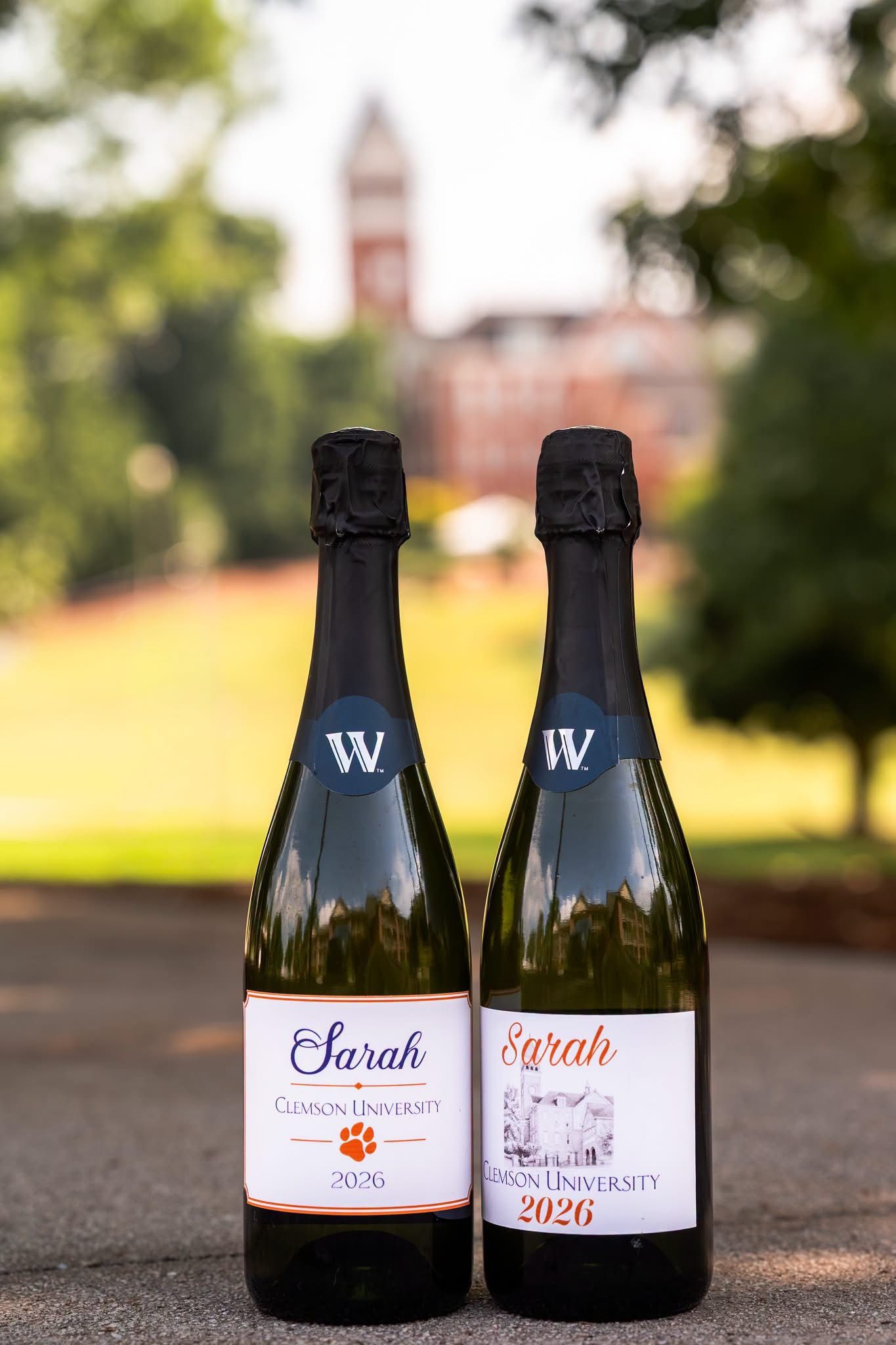 Two custom Clemson University 2026 labeled sparkling wine bottles named Sarah, photographed outdoors near a historic campus building.