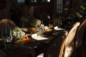 Elegant wedding reception table with floral centerpieces and glassware in dramatic moody lighting.
