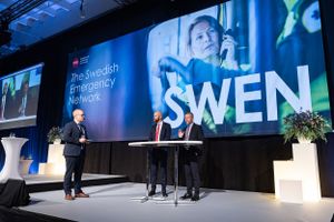 Eventfotography of a professional conference stage setup with SWEN text displayed on large screen and speakers presenting at podium.