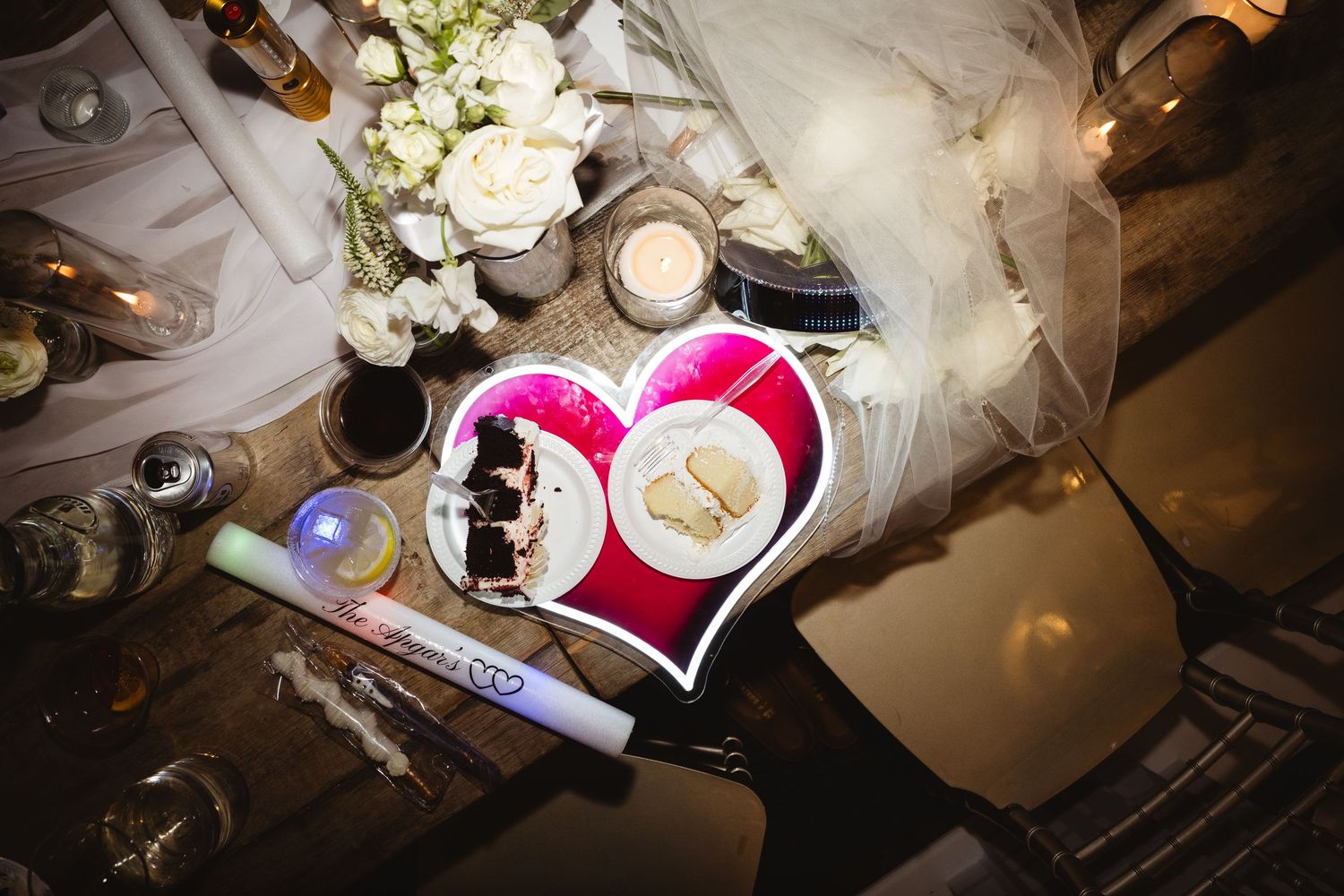 Wedding table decor with heart-shaped photo frame, white roses, candles, and bridal veil in elegant reception setting.