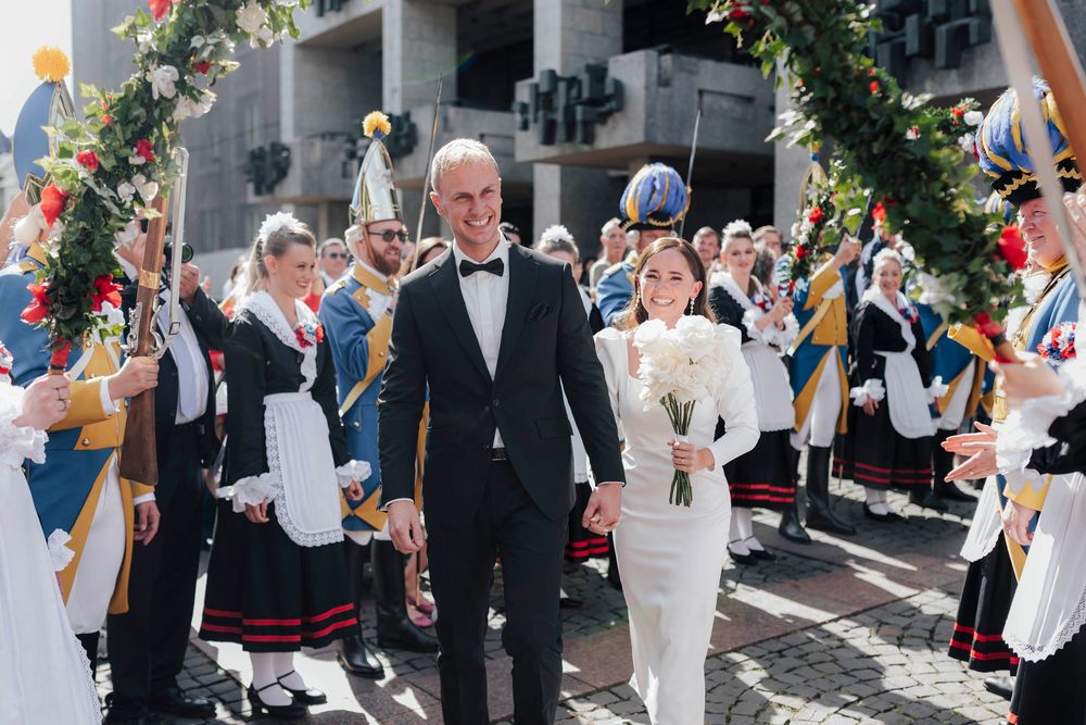 Bride and groom walk through a traditional folk dance guard of honor at their outdoor wedding ceremony.