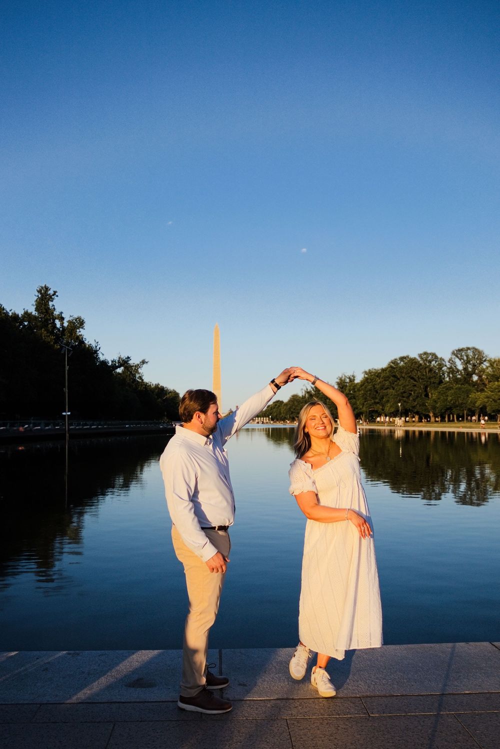 Couple dancing by the Reflecting Pool with the Washington Monument at golden hour in DC.