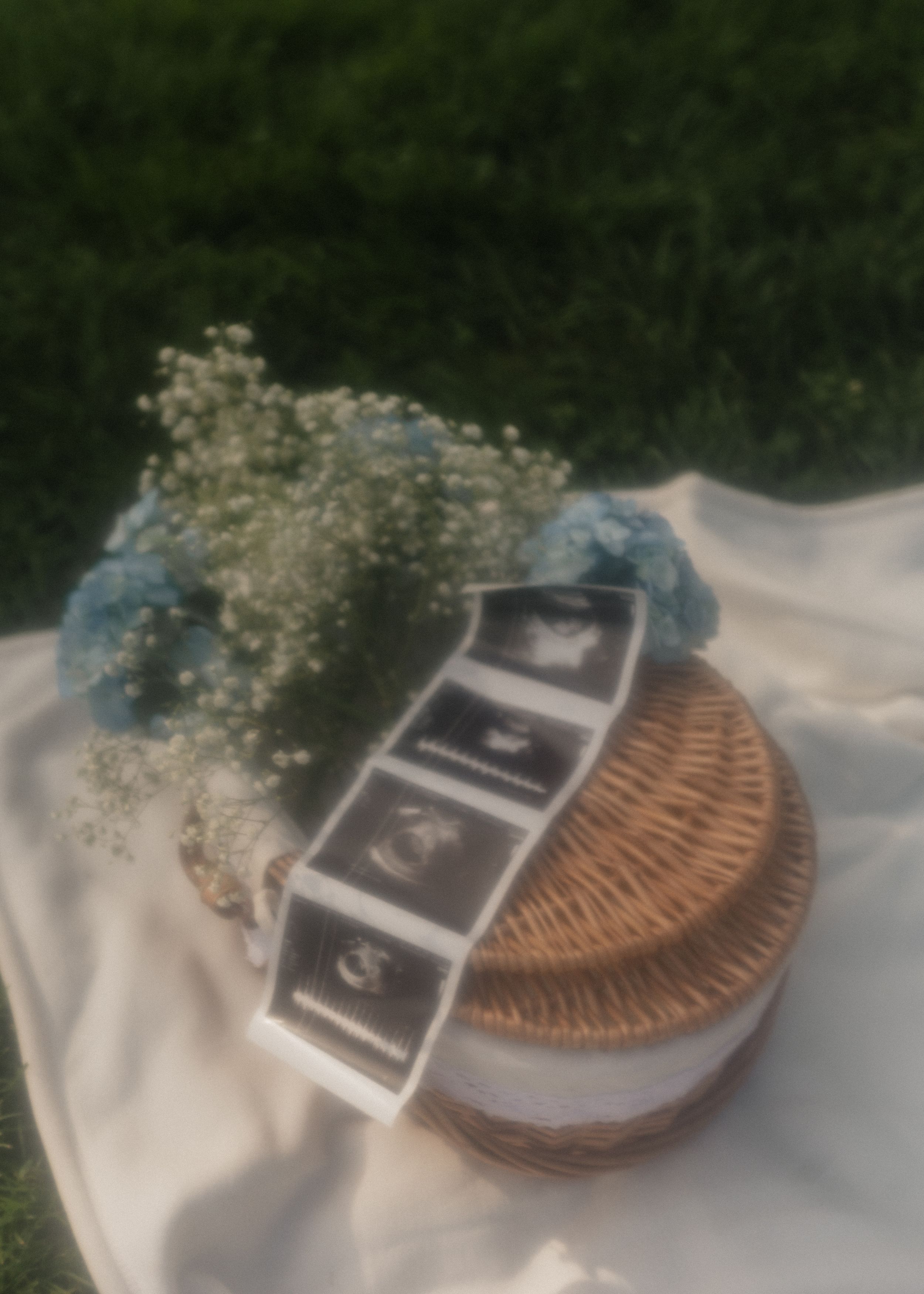 Ultrasound scan strip placed beside a woven basket with white fabric and baby's breath flowers on a grassy surface.