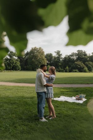 Two people sharing an intimate moment together on a lush green field during a summer afternoon.