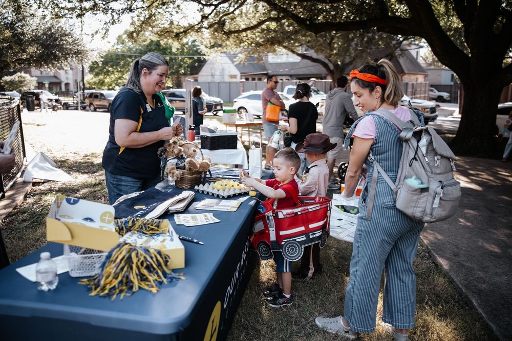 Vendor table with cheese and food samples at an outdoor fall festival with families browsing.
