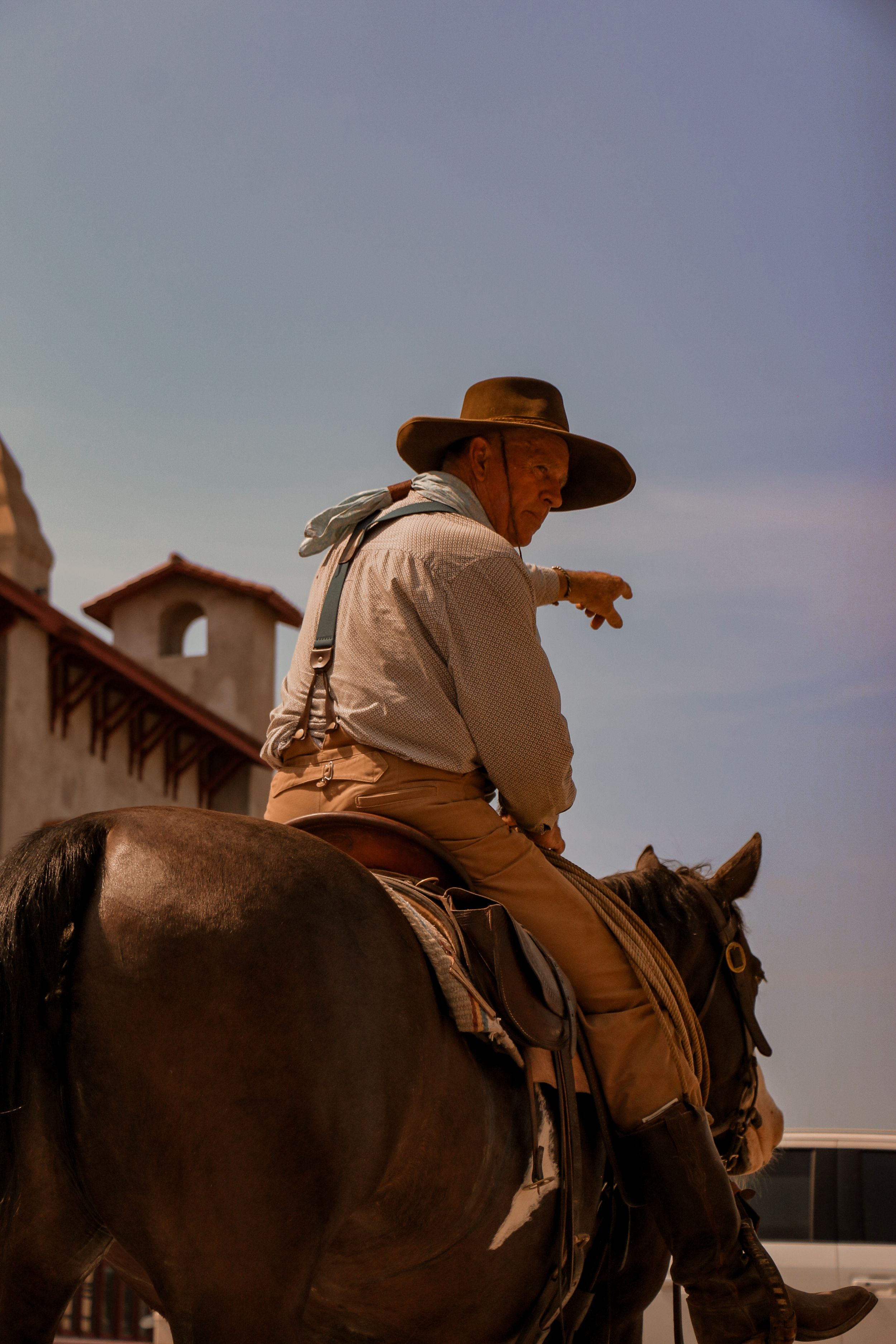 Silhouette of a cowboy on horseback against a Spanish colonial building backdrop.