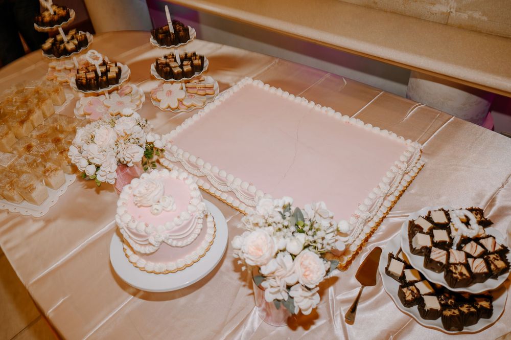 Elegant quinceañera dessert table featuring a white sheet cake, floral decorated smash cake, and chocolate brownies.