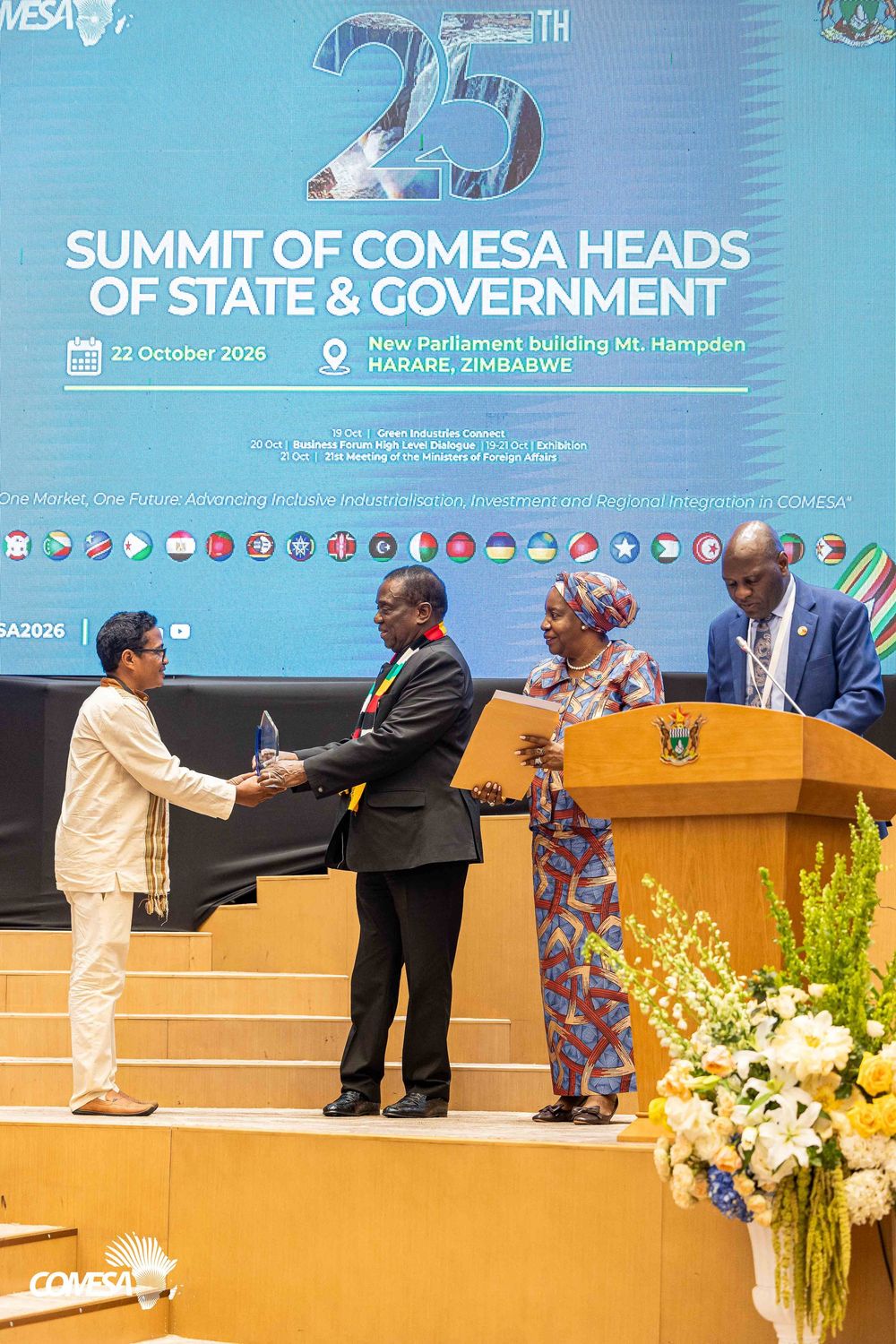 Delegates exchange a handshake and gift on stage at the 25th COMESA Summit of Heads of State and Government in Harare, Zimbabwe.