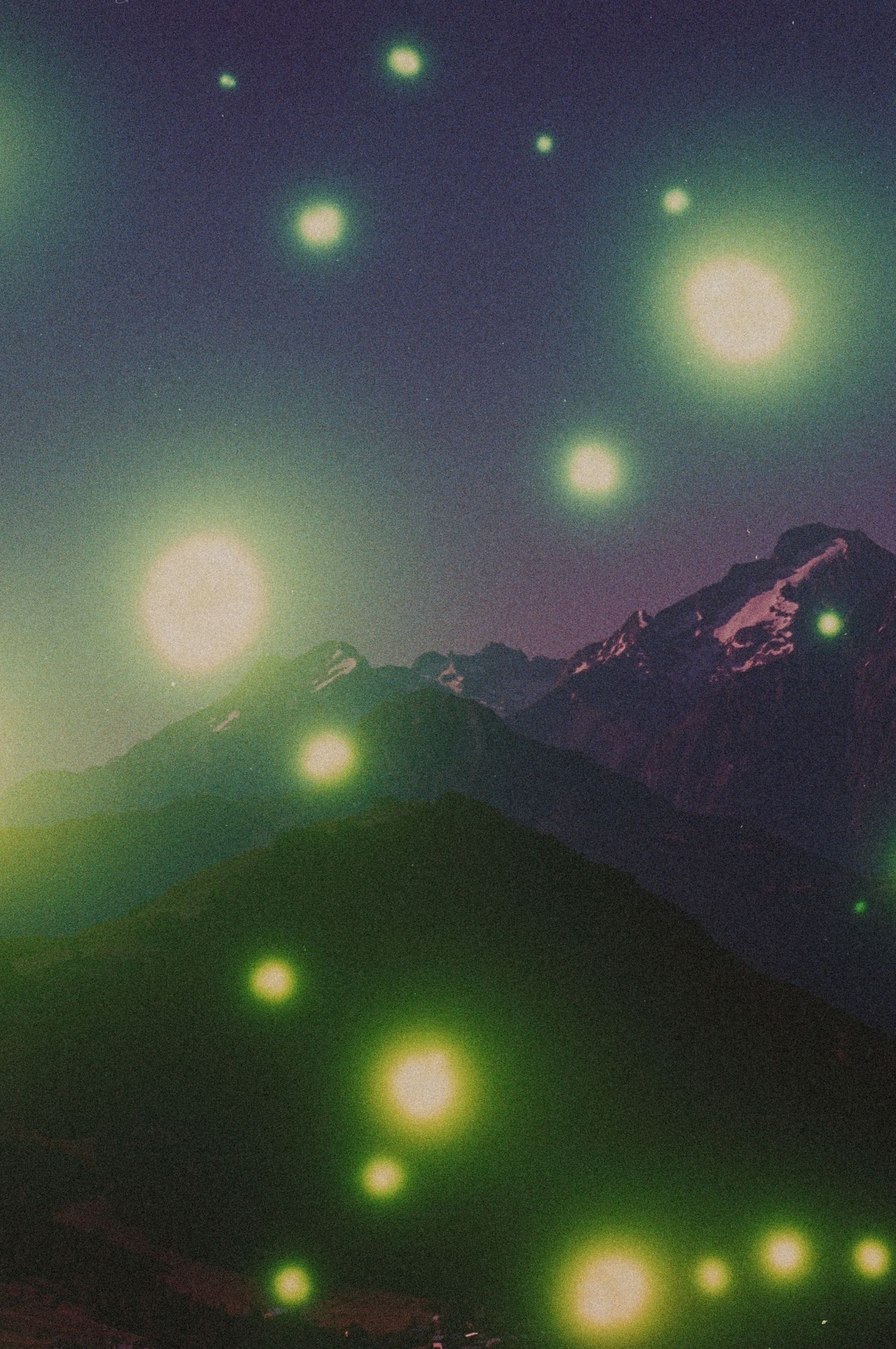 Night mountain landscape with glowing orbs of light scattered across a dark green sky above snowy peaks.