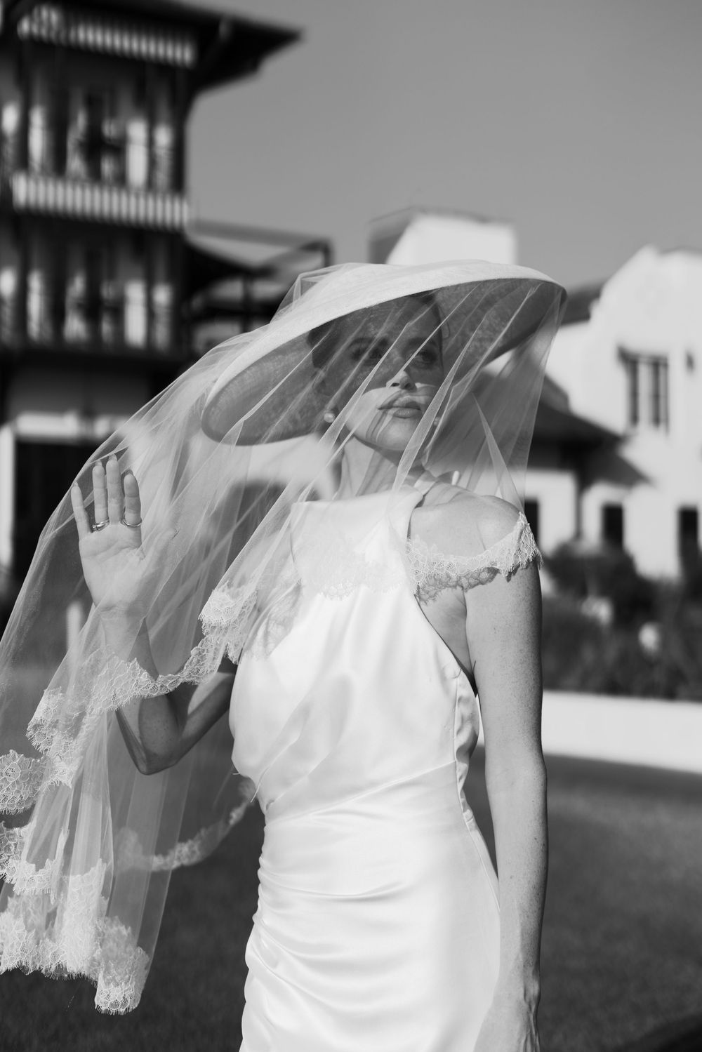 Black and white photo of a bride in a white dress and lace veil outdoors.