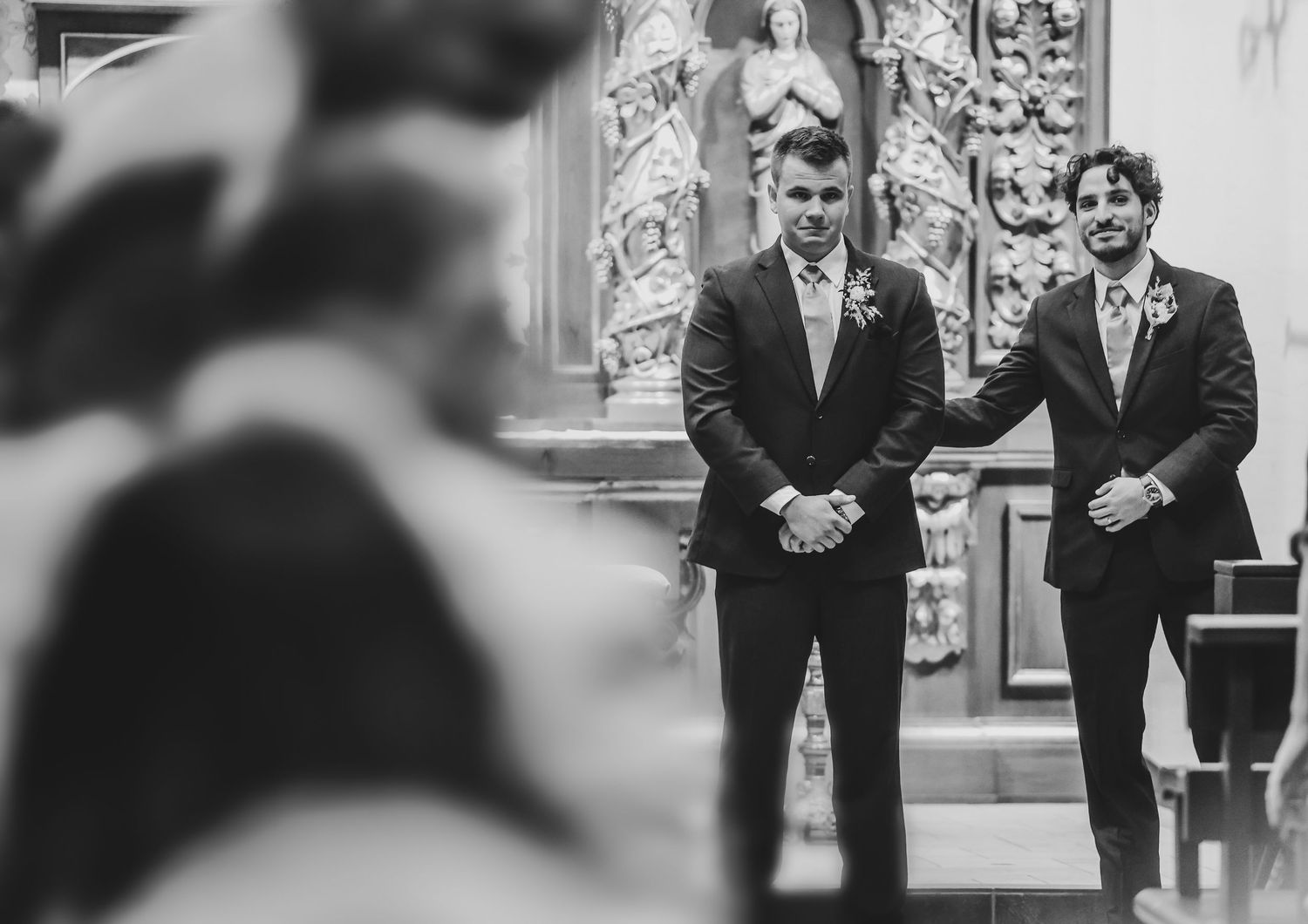 Groom watching bride walk down aisle at Catholic wedding ceremony