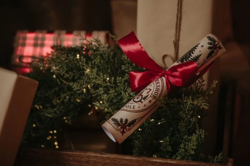 A Christmas letter tied with a red ribbon among festive greenery, from a previous session.