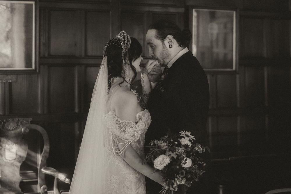 Black and white wedding photo of bride and groom sharing an intimate moment, bride holding floral bouquet.
