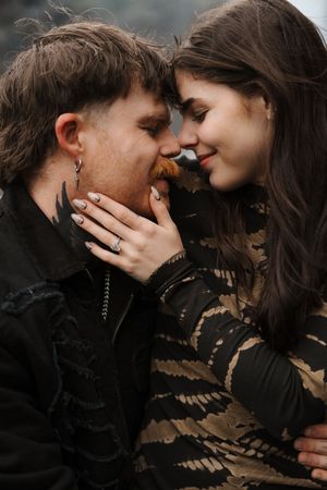 A romantic couple shares an intimate moment, touching foreheads, as the woman gently cups the man's face.