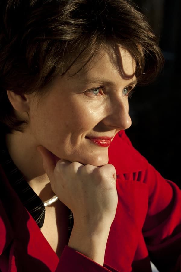Portrait professionnel d’une femme en veste rouge, photographiée sur fond sombre avec un éclairage latéral. D.Seven  ,pianiste