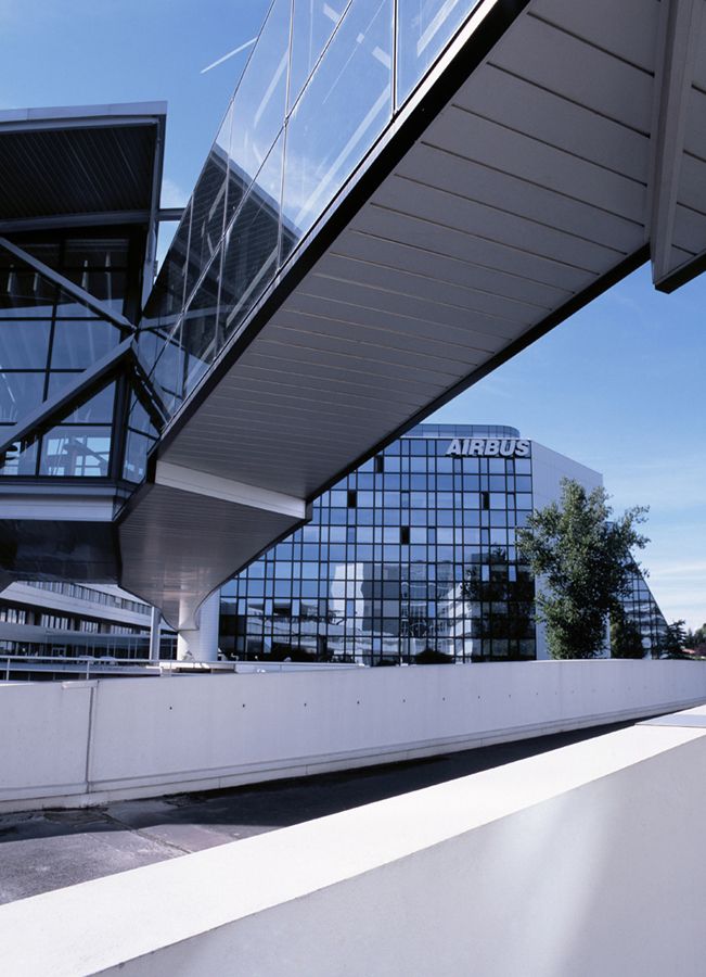 Architecture industrielle contemporaine avec passerelle métallique et façades vitrées sur le site Airbus de Bordeaux.