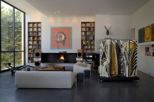 Salon contemporain avec grandes baies vitrées, cheminée, mobilier design et œuvres d’art.