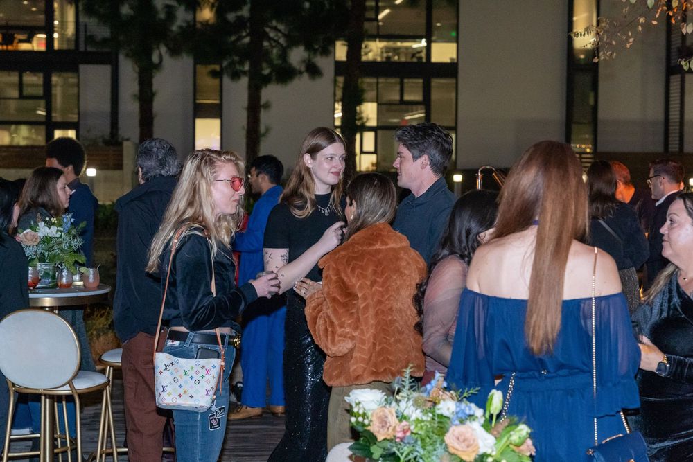 Guests mingling at an elegant evening networking event with floral arrangements and ambient lighting.