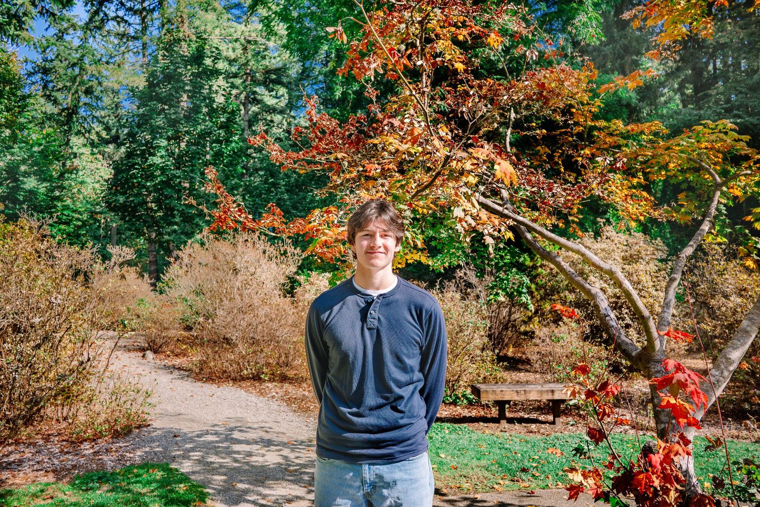 Senior standing along a garden path surrounded by colorful fall foliage at Lake Wilderness Park