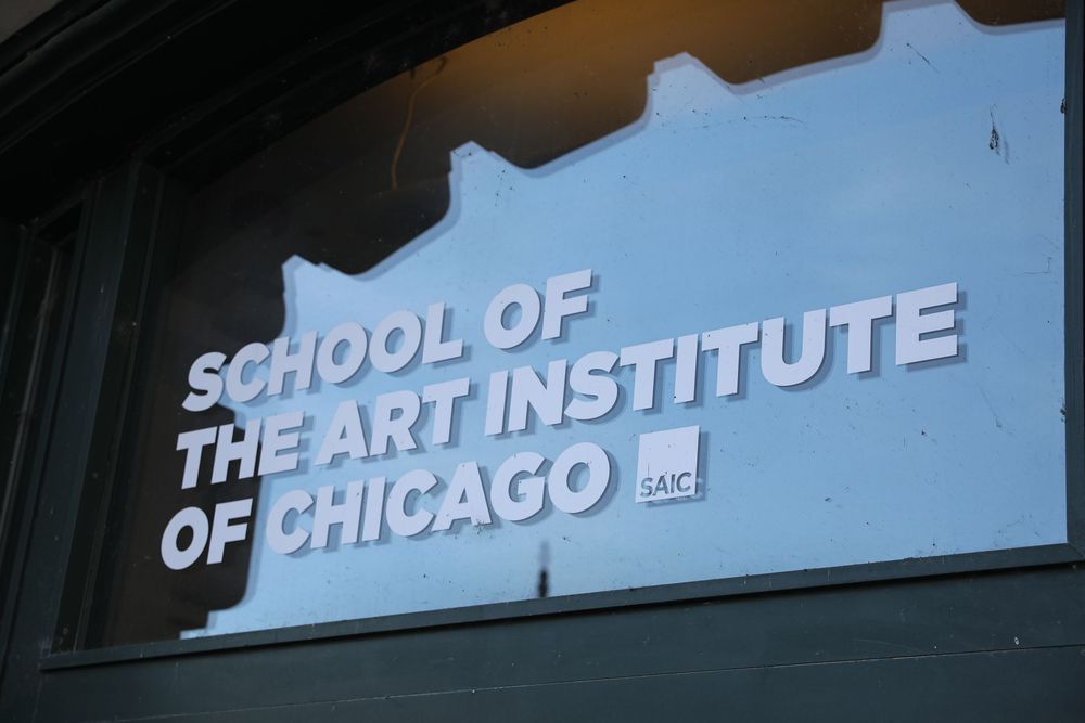 Sign for the School of the Art Institute of Chicago (SAIC) displayed on a window or wall.