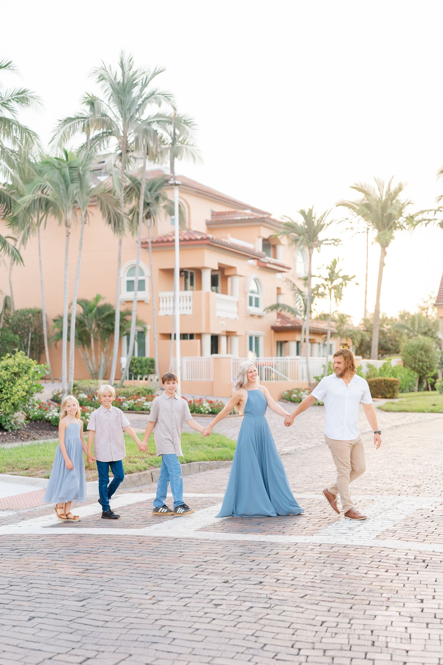 family in downtown st. Pete Vinoy Park walking across the brick road hand in hand during their family photoshoot