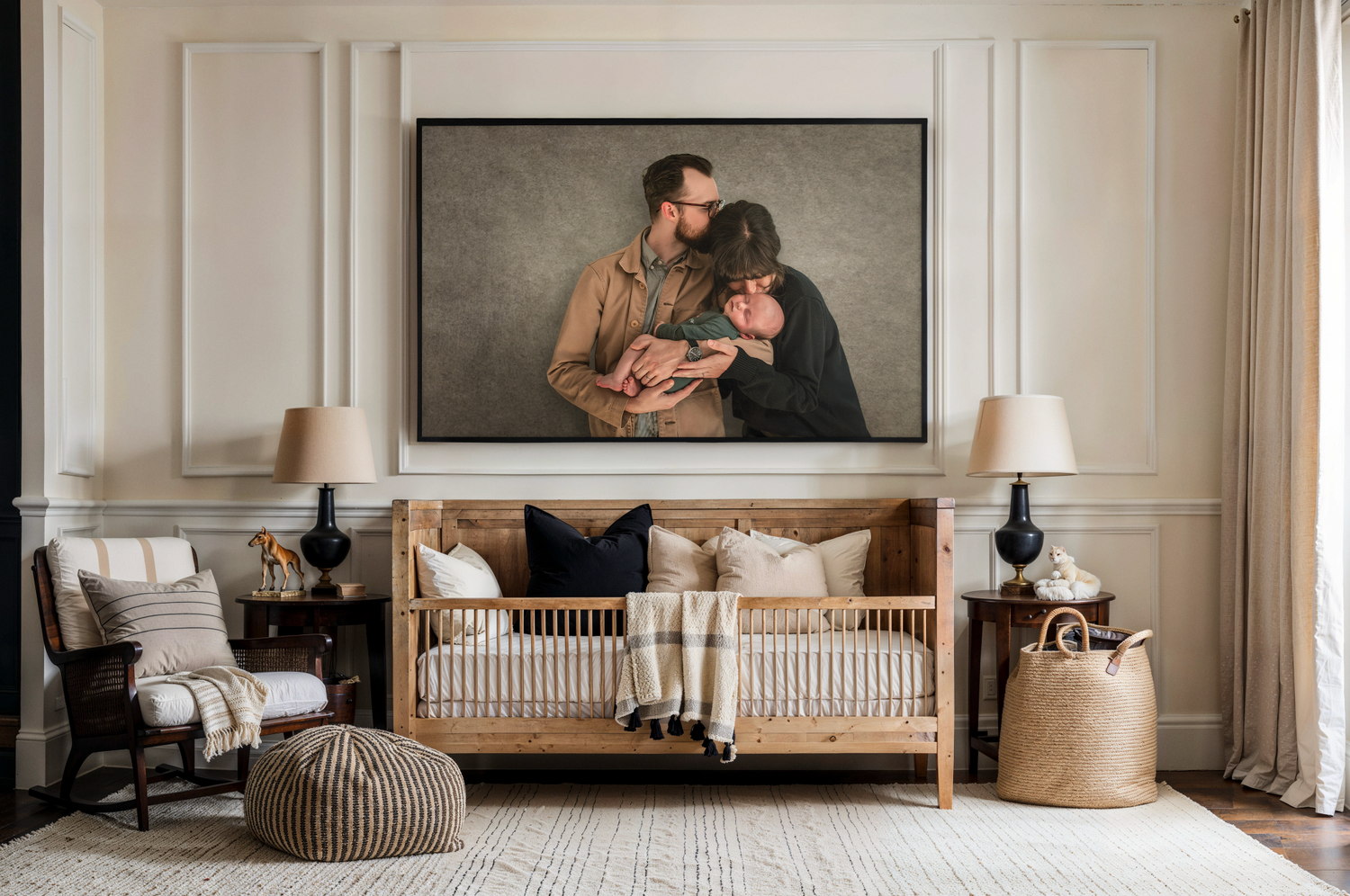 Elegant nursery with a large framed family portrait above a wooden crib, flanked by lamps and neutral decor.