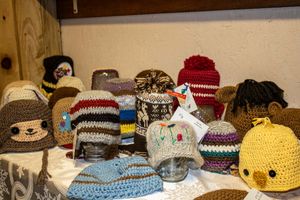 Colorful handmade crochet knit hats displayed on a shelf, featuring various styles and patterns for all ages.