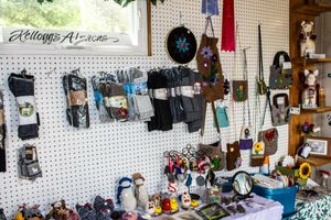 Kelloggs Alterations shop interior with handmade crafts, purses, and accessories displayed on a white pegboard wall.