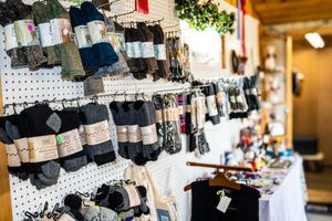 A retail display of colorful wool socks hanging on a pegboard wall in a cozy gift shop.