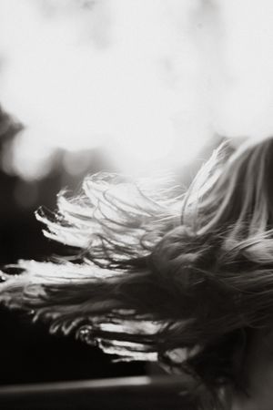 Black and white photo of long hair blowing in the wind, captured with artistic motion blur effect.