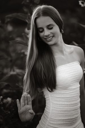 Beautiful young woman with long hair in white strapless dress smiling, black and white portrait.