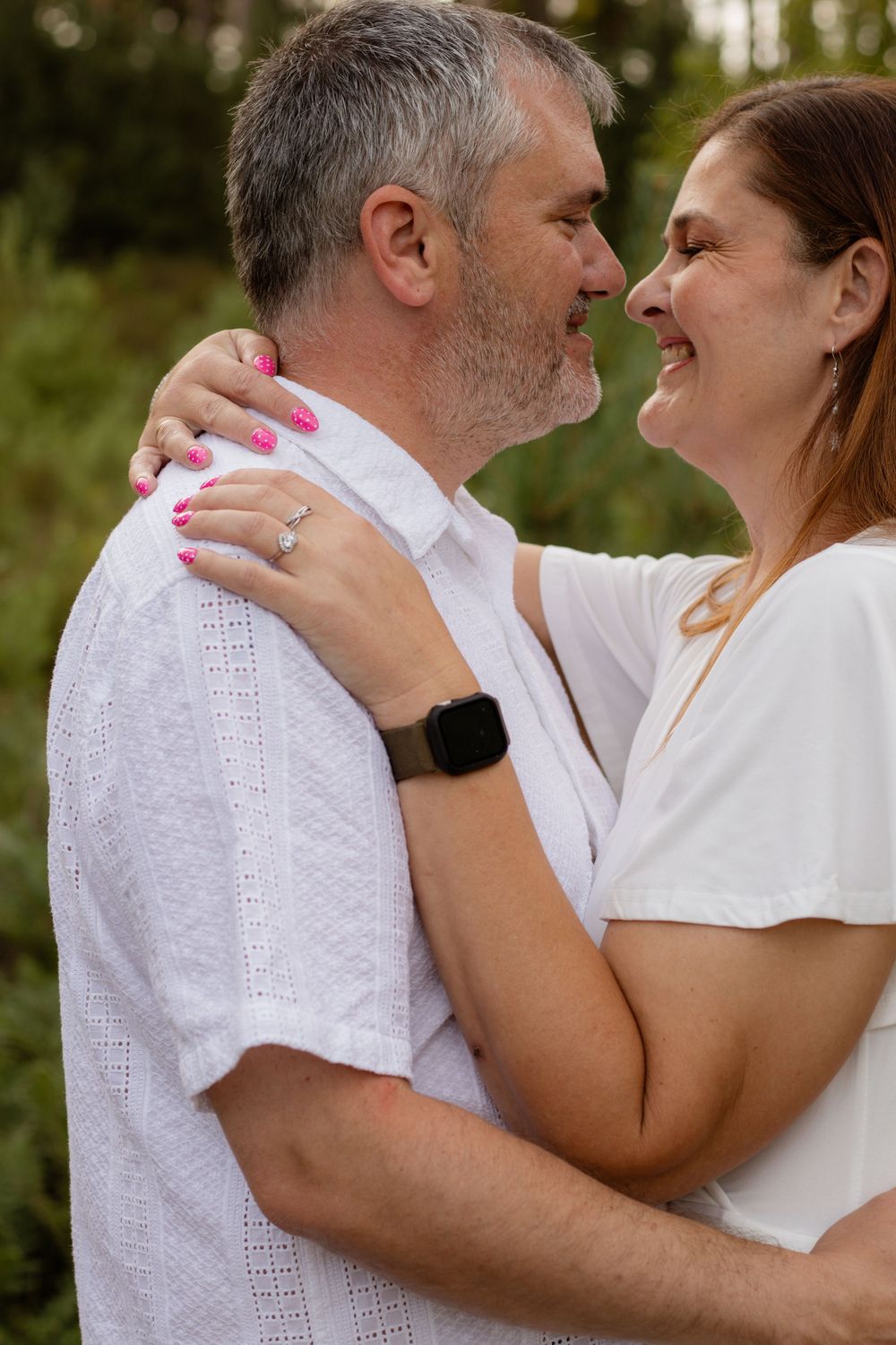 Smiling couple gazing at each other in an outdoor embrace.