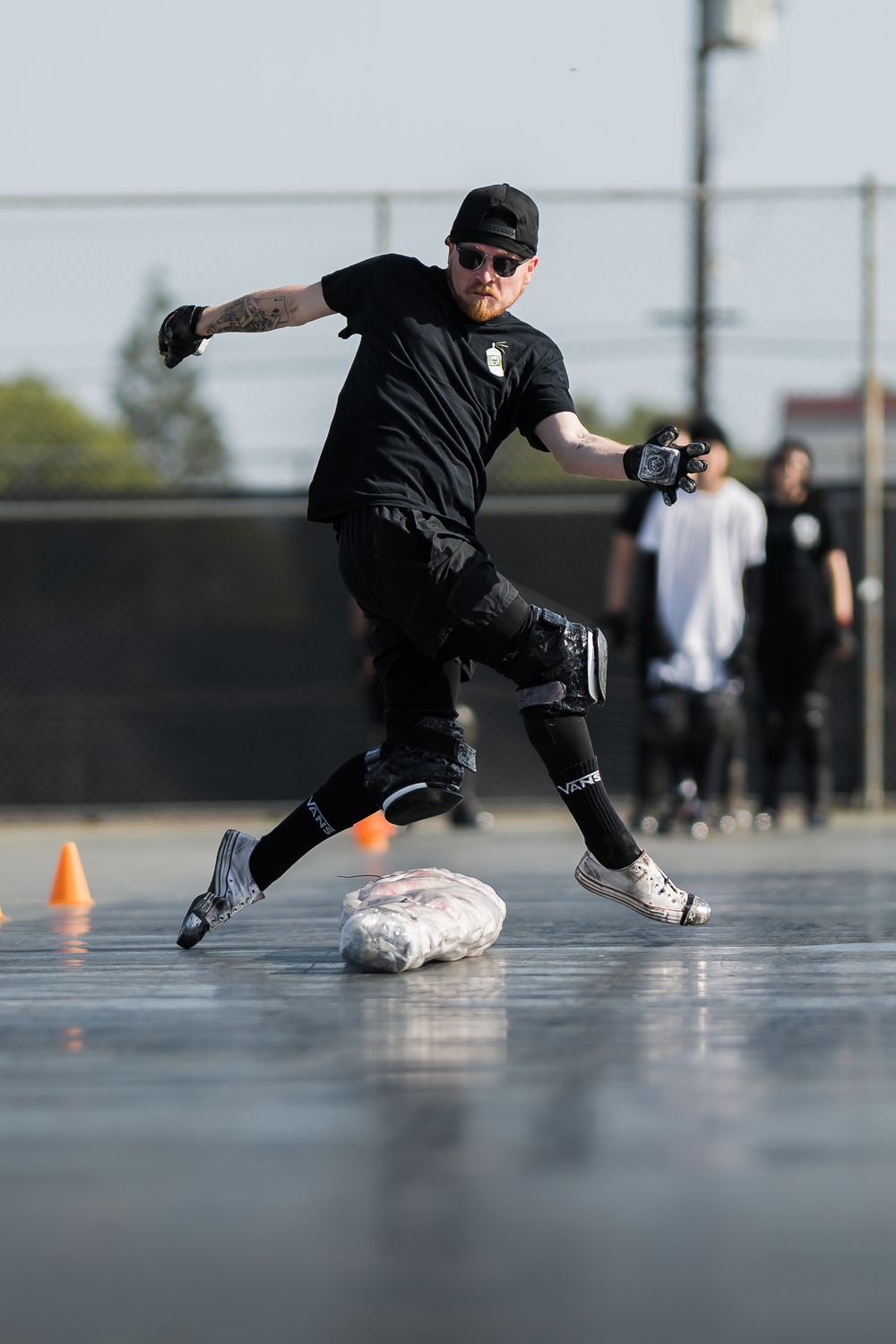 Decayed Brigade performer crouches low mid-slide with sparks flying from gloves during a nighttime practice session.