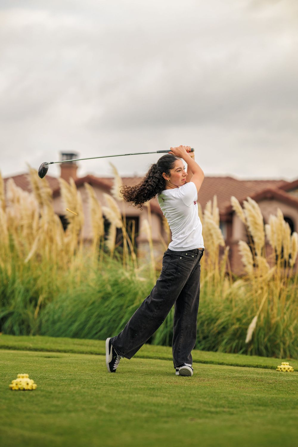 OLu women’s golf athlete swings her club on the course during a match, captured by Chris Cornish Photography.
