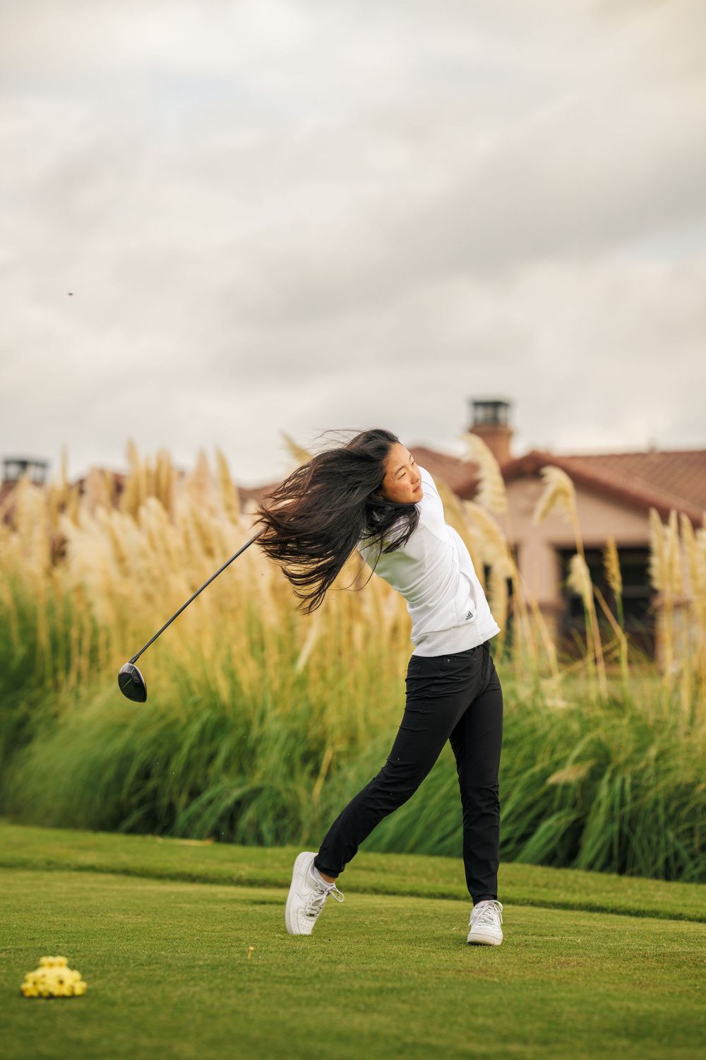 OLu women’s golf athlete swings her club on the course during a match, captured by Chris Cornish Photography.