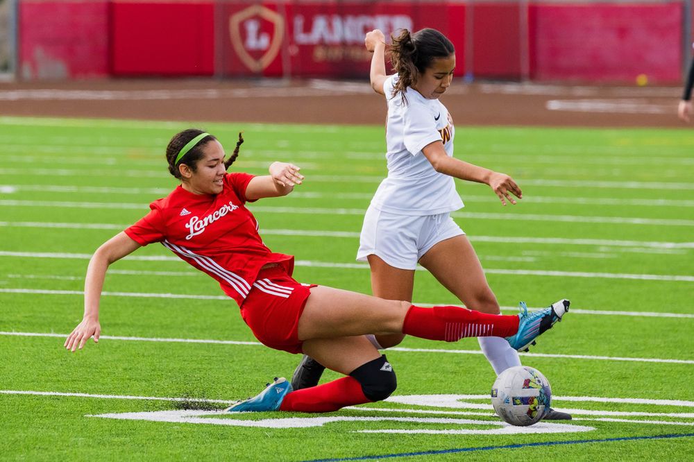 OLu women’s soccer player slides toward the ball during a game, captured by Chris Cornish Photography.
