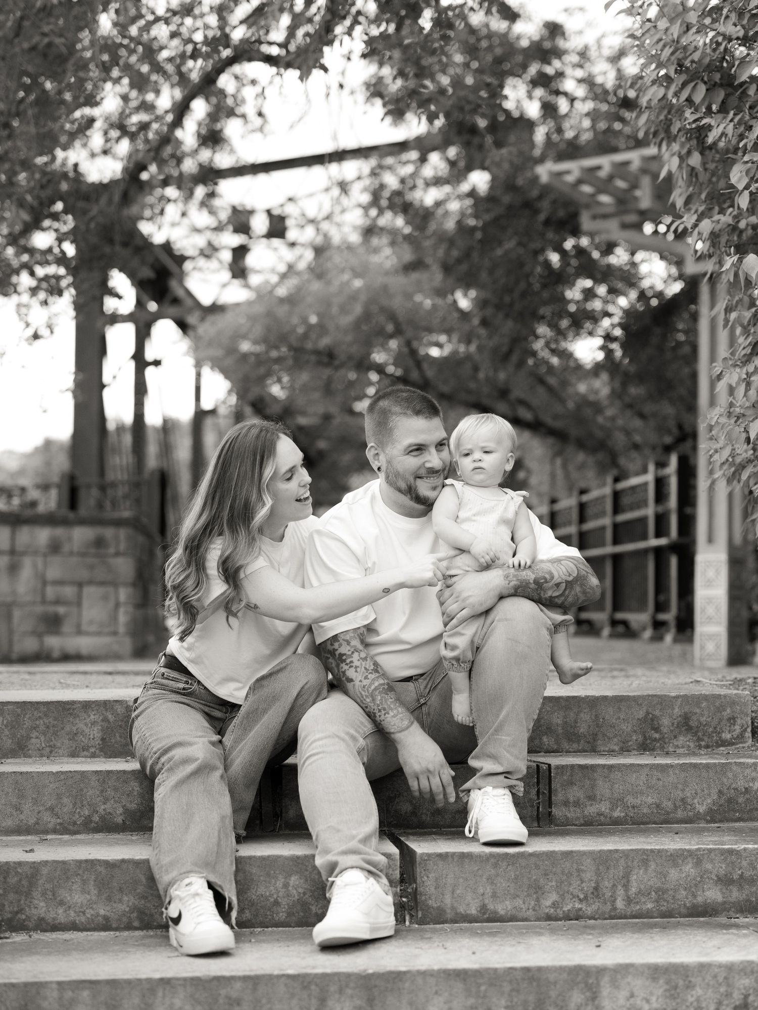 Family with baby sitting on stone steps in a black and white portrait.