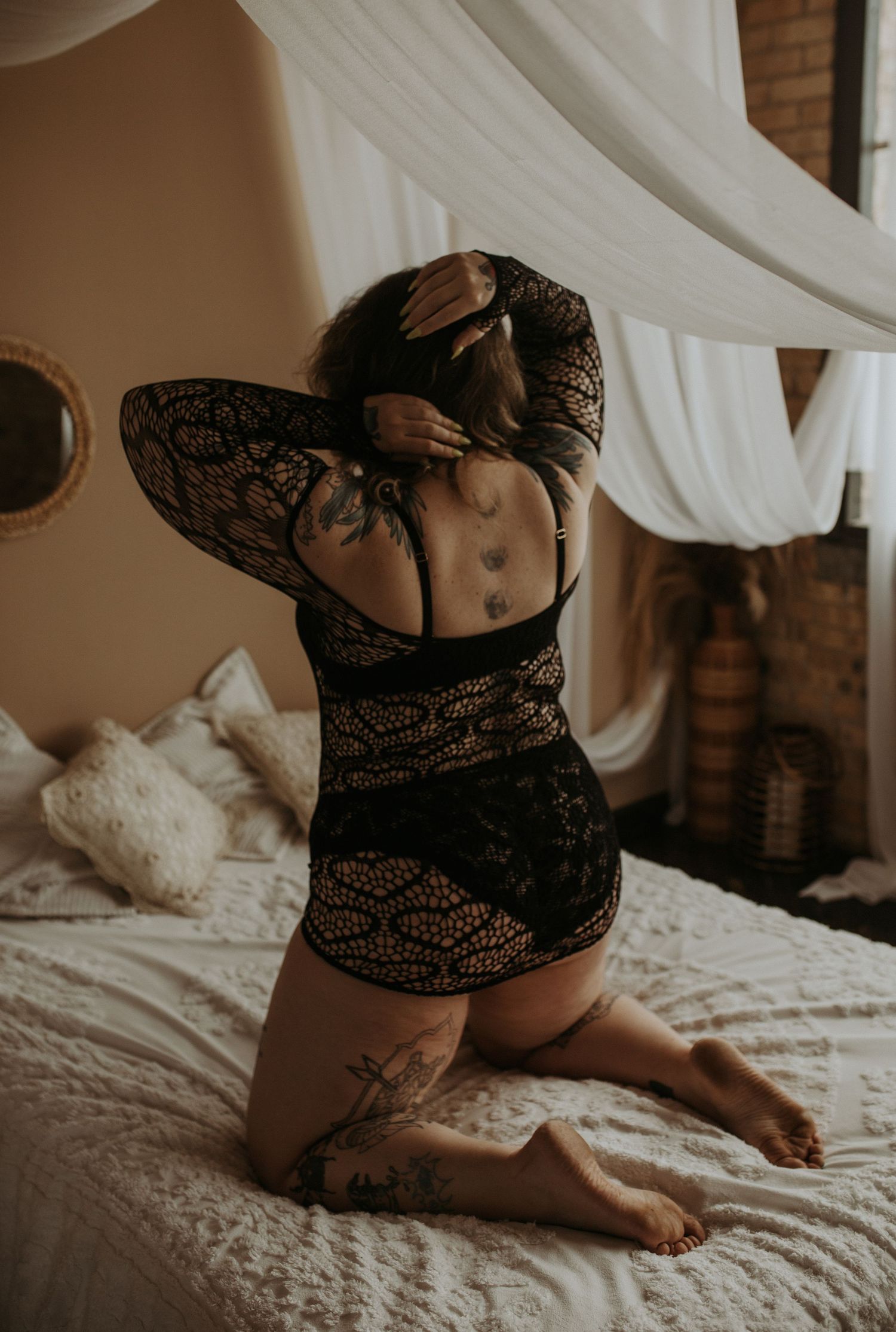 A person with locs resting in a vintage clawfoot bathtub, captured in moody, artistic boudoir photography.