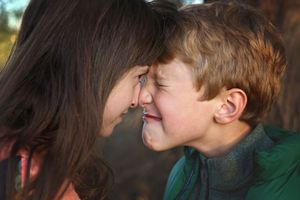 A girl and a boy press their foreheads together, the boy scrunching his face in a playful, silly expression.