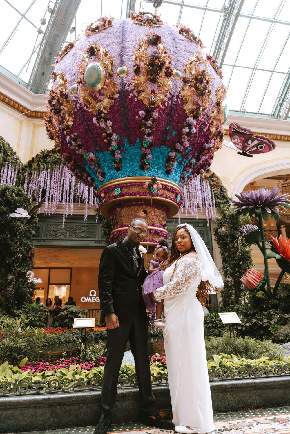 A bride and groom pose in front of a floral hot air balloon display inside the Bellagio conservatory in Las Vegas.