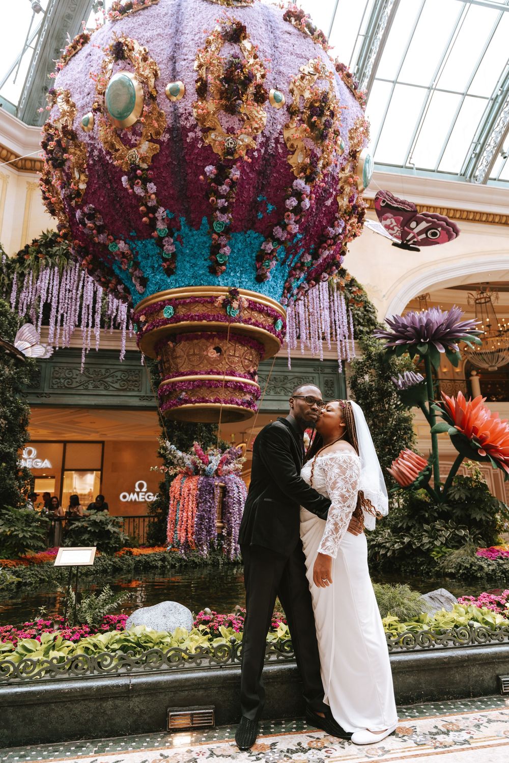 Newlywed couple kissing in front of floral hot air balloon display at Bellagio Conservatory Las Vegas.
