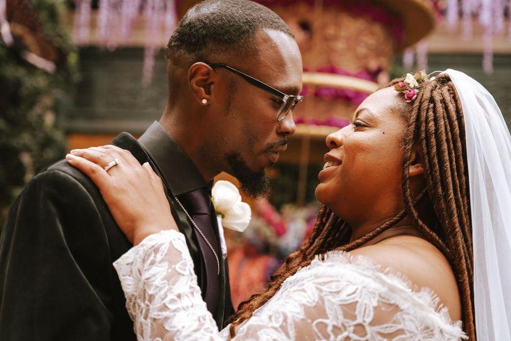 A bride and groom share an intimate moment at their wedding, with the bride wearing a white veil and lace dress.