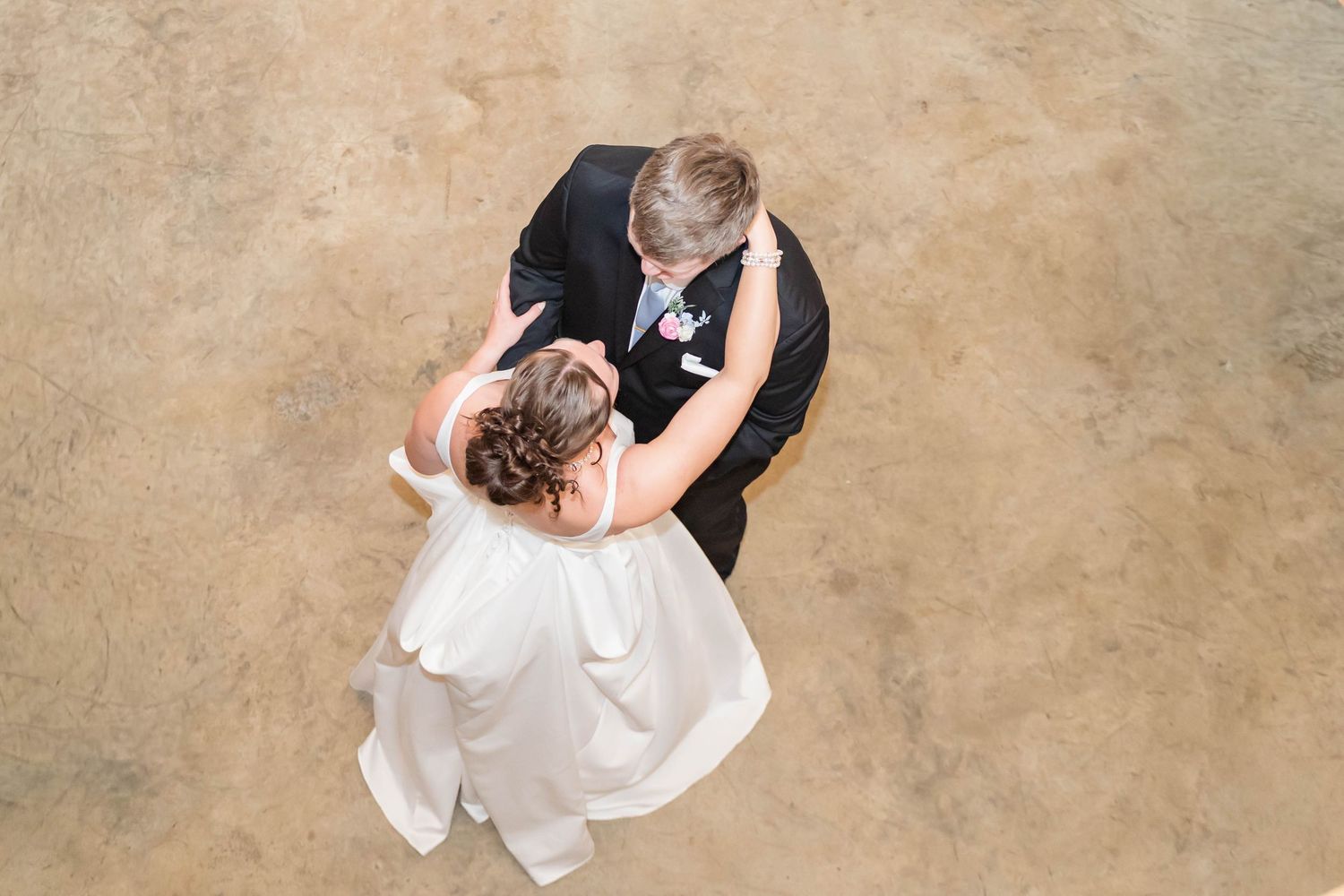Aerial view of bride and groom sharing their first dance, captured from above on a wedding day.