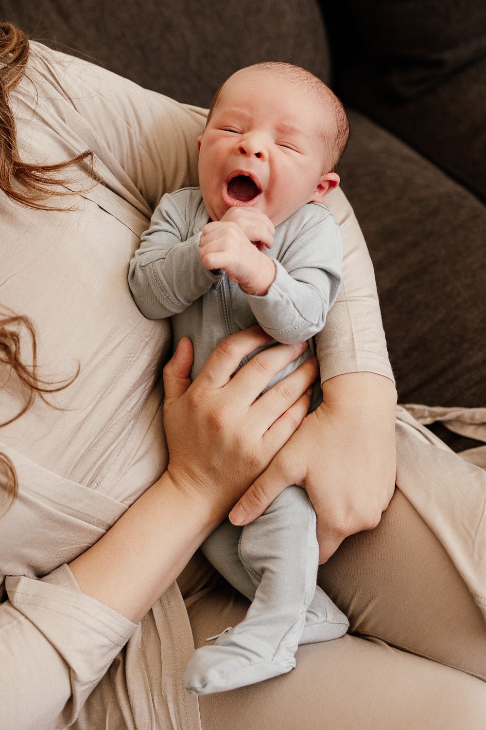 Mom holds her newborn baby boy while he gives a big yawn