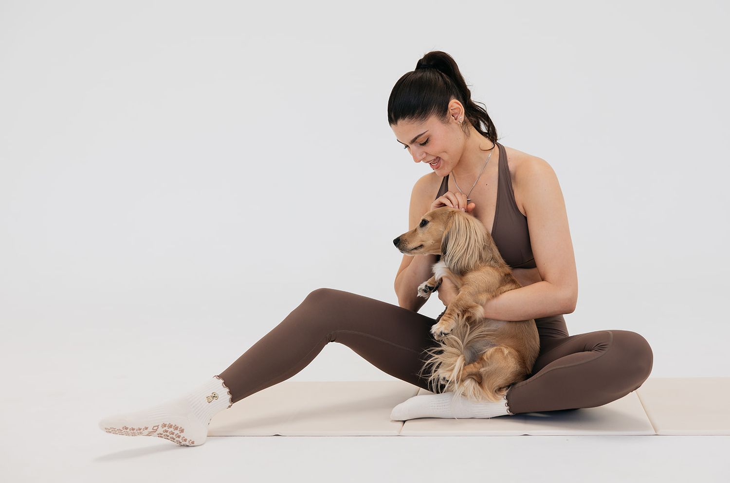 A fluffy golden doodle puppy perched on a raised leg wearing light blue leggings and white socks.