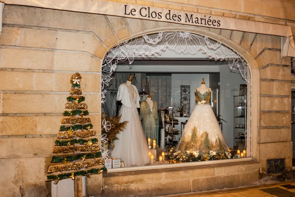 Le Clos des Mariées bridal boutique storefront with elegant wedding gowns displayed in a festive Christmas window.