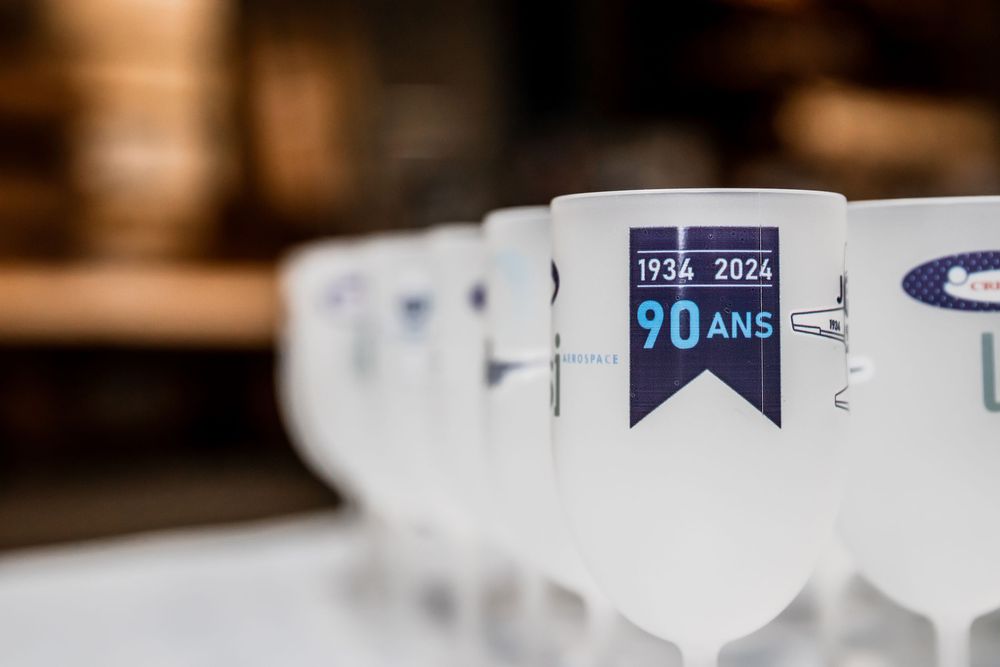 Row of white goblets celebrating 90 years anniversary 1934-2024, elegantly displayed in a line.