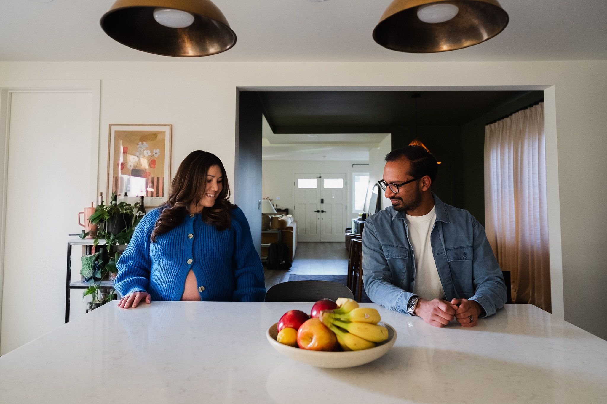 Expecting couple sitting together at the kitchen island during their at home maternity session